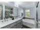 Bright bathroom featuring a double vanity with gray cabinets, a soaking tub, and a glass-enclosed shower at 1547 Paxton Sw Dr, Lilburn, GA 30047