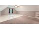 Attic bedroom space with mixed flooring, a ceiling fan, and natural light, alongside storage shelves at 245 Sutallee Ridge Ne Ln, White, GA 30184