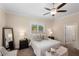 Bright main bedroom featuring neutral tones, a ceiling fan, and large window overlooking the green outdoors at 4457 Equity Ct, Ellenwood, GA 30294