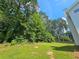 Spacious backyard with green grass, mature trees, and a glimpse of the home's exterior at 1471 Ashwood Way, Lawrenceville, GA 30043