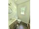 Bright powder room features a round mirror, vanity, and natural light from the window at 1471 Ashwood Way, Lawrenceville, GA 30043
