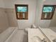Bathroom with a window, toilet, tub and a large mirror above the sink at 1471 Ashwood Way, Lawrenceville, GA 30043