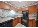 This kitchen has wooden cabinetry, black appliances, and floral wallpaper at 1800 Clairmont Lk # 630, Decatur, GA 30033