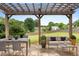 Underneath a wooden pergola, outdoor seating and dining offer views of the green backyard at 3340 Deerwood Ln, Rex, GA 30273