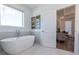 Bright bathroom featuring a standalone tub, neutral walls, and an open doorway to the living area at 1011 Crown Oak St # 47, Johns Creek, GA 30022