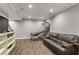 Finished basement with gray walls, hardwood floors, modern recessed lighting, a bookshelf, a couch, and a basketball game at 141 Ennisbrook Se Dr, Smyrna, GA 30082