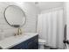 Modern bathroom featuring shiplap walls, a round mirror, and a navy blue vanity at 141 Ennisbrook Se Dr, Smyrna, GA 30082