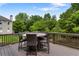 Wooden deck with a round outdoor dining set and an overview of the tree-filled backyard, perfect for entertaining at 141 Ennisbrook Se Dr, Smyrna, GA 30082
