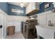 Charming laundry room with blue walls, wainscoting, washer, dryer, wash basin, and white cabinets at 141 Ennisbrook Se Dr, Smyrna, GA 30082