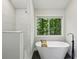 Bright bathroom featuring a standalone tub and walk-in shower with marble wall tile at 545 Woodman Pl, Roswell, GA 30076