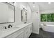 Bright bathroom with double sinks, white cabinetry, sleek fixtures, a standalone tub and walk-in shower at 545 Woodman Pl, Roswell, GA 30076