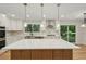 Modern kitchen boasts a center island, stainless appliances, hardwood floors and stylish pendant lighting at 545 Woodman Pl, Roswell, GA 30076