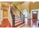 Bright foyer featuring hardwood floors, stairs with decorative iron railing and white trim at 116 Archstone Sq, Mcdonough, GA 30253