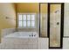 Bright bathroom features a large soaking tub and separate glass-enclosed shower with tiled surround at 116 Archstone Sq, Mcdonough, GA 30253