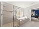 Bright bathroom featuring a walk-in shower, soaking tub, and view into the blue bedroom at 5157 Sunlake Dr, Hoschton, GA 30548
