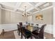 Elegant dining room featuring hardwood floors, coffered ceiling, wainscoting, and stylish chandelier at 5157 Sunlake Dr, Hoschton, GA 30548
