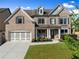 Charming brick home featuring a well-manicured lawn, attached garage, and inviting front porch with seating at 5157 Sunlake Dr, Hoschton, GA 30548