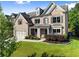 Beautiful two-story brick home featuring mature landscaping, an attached garage and an inviting front porch at 5157 Sunlake Dr, Hoschton, GA 30548