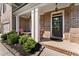 Inviting front porch featuring white columns, a brick facade, lush landscaping, and charming outdoor seating at 5157 Sunlake Dr, Hoschton, GA 30548