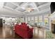 Open-concept living room featuring a coffered ceiling, fireplace, hardwood floors, and access to the kitchen at 5157 Sunlake Dr, Hoschton, GA 30548
