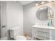 Modern bathroom with white vanity, round mirror, decorative flowers, and sleek walk-in shower with glass door at 83 Shipp Cir, Hiram, GA 30141