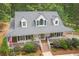 Aerial view of a charming two-story farmhouse with a full-length porch, white siding, and manicured landscaping at 83 Shipp Cir, Hiram, GA 30141