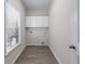 Well-lit laundry room with storage cabinets, window, and wood-look floors at 1666 Baxley Pine Trce, Suwanee, GA 30024