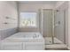 Bright bathroom featuring a soaking tub, separate shower, and tiled walls at 1666 Baxley Pine Trce, Suwanee, GA 30024
