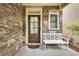 Inviting stone-accented front porch featuring a stylish front door and a cozy white bench at 8360 Village School Dr, Cumming, GA 30041