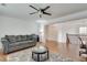 Open living room featuring hardwood floors, gray couch, and ceiling fan at 8360 Village School Dr, Cumming, GA 30041