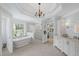 This bathroom features a freestanding tub, glass enclosed shower, white cabinets, and unique chandelier at 7615 Laurel Oak Dr, Suwanee, GA 30024