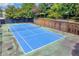 A blue tennis court surrounded by mature shade trees and a stone wall for neighborhood recreation at 1250 Parkwood Se Cir # 1213, Atlanta, GA 30339