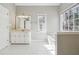 Well-lit bathroom featuring white cabinetry, tile floors, large mirror, and large window for natural light and ventilation at 4271 Weston Sw Dr, Lilburn, GA 30047