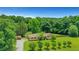 Aerial view of a well-maintained home with a brick facade, gravel driveway, and lush greenery at 3332 Oak Grove Rd, Loganville, GA 30052