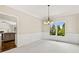 Dining room with wainscoting, chandelier, large window, and view into the kitchen at 11100 Chandon Way, Johns Creek, GA 30097