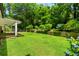 Backyard showcasing a lush, green lawn, beautiful landscaping, and a tiered garden wall for added character at 1492 Sagewood Cir, Stone Mountain, GA 30083