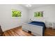 Cozy bedroom with hardwood floors, a white bed frame, side tables, and windows overlooking a green landscape at 1492 Sagewood Cir, Stone Mountain, GA 30083