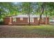 The backyard of this home showcases mature trees, a brick house, and a patio at 2858 Valley Ridge Dr, Decatur, GA 30032