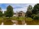 Picturesque backyard view of a two-story home with a covered patio overlooking a serene pond at 638 Glen Valley Way, Dacula, GA 30019