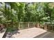 A wood back deck with wood railing provides an outdoor space surrounded by mature trees and greenery at 194 Lake Ruby Dr, Suwanee, GA 30024