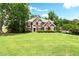 Beautiful red brick home showcasing a large green lawn and mature trees at 194 Lake Ruby Dr, Suwanee, GA 30024