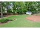 Expansive backyard with a storage shed, green grass, and a mulched area surrounded by lush trees at 402 Princeton Way, Lawrenceville, GA 30044