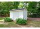 White storage shed with double doors, nestled among greenery in the backyard, providing extra storage space at 402 Princeton Way, Lawrenceville, GA 30044
