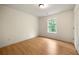 Bedroom with hardwood flooring, window overlooking greenery, ceiling light, and white door at 4095 Oriole Ln, Fairburn, GA 30213
