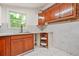View of a kitchen with wood cabinets, light countertops, white floors, and a sink under a window at 574 Hickory Hills Ct, Stone Mountain, GA 30083