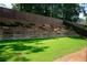 A grassy backyard featuring a retaining wall and wood fence for privacy at 2159 Holland Creek Ln, Buford, GA 30519