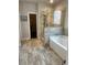 Modern bathroom with a separate shower and soaking tub with neutral tile throughout the space at 2159 Holland Creek Ln, Buford, GA 30519