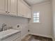 Well-lit laundry room features ample storage with upper cabinets, a sink and tile flooring at 3487 Binghurst Rd, Suwanee, GA 30024