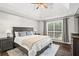 Bedroom featuring a dark wood frame bed, ceiling fan, and a large window at 6065 Ashbury Ln, Cumming, GA 30028