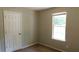Bedroom featuring a window with blinds, a door, and neutral-colored walls at 330 Christian Woods Dr, Conyers, GA 30013